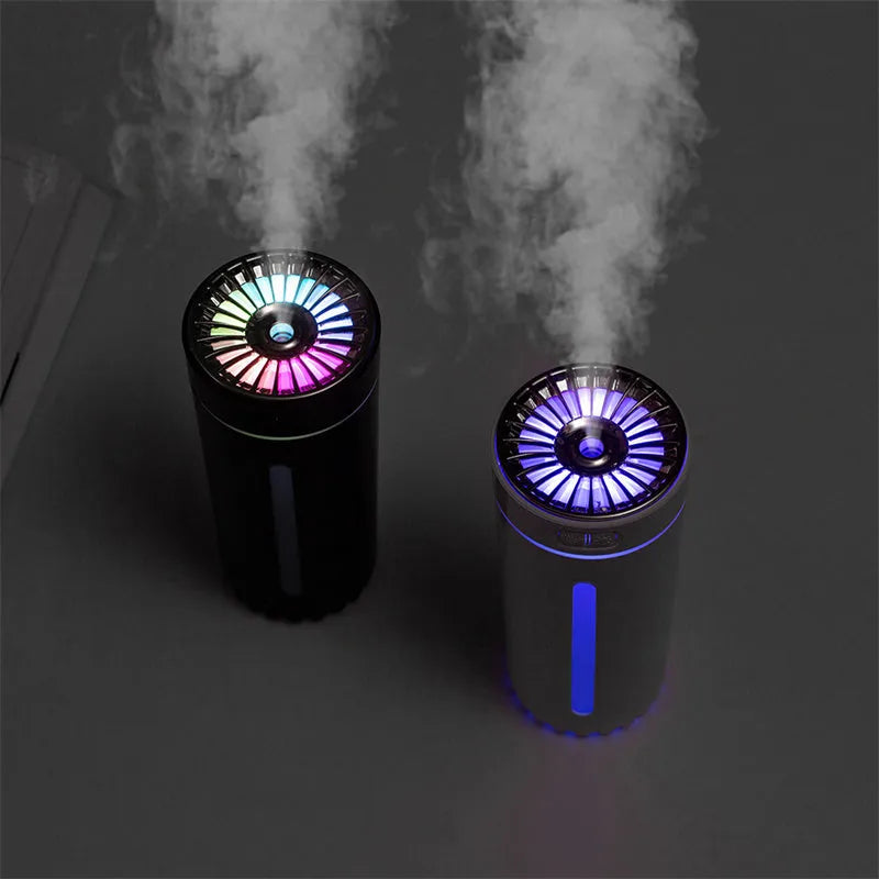 Black portable ultrasonic humidifier with colourful LED lights, shown next to a USB cable on a desktop.