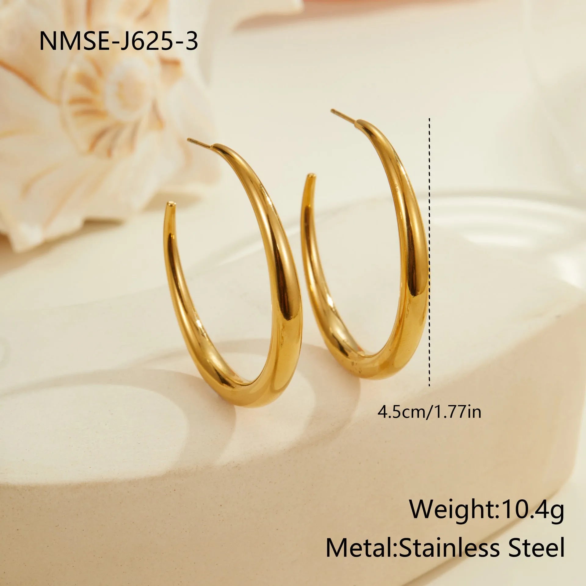 A pair of simple round titanium steel hoop earrings in a gold finish on a white background.
