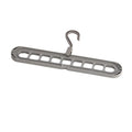 Green plastic nine-hole folding hanger for trousers shown in a dormitory wardrobe.