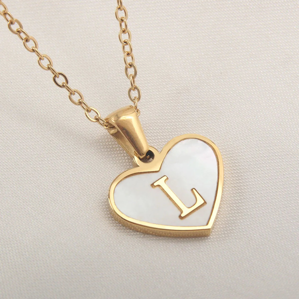 Gold heart necklace with white shell detail and personalised initial letter on adjustable chain