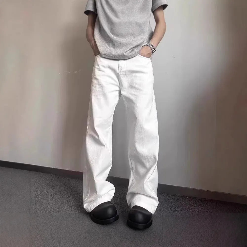 Man wearing loose straight-leg white denim jeans with a wide leg opening.