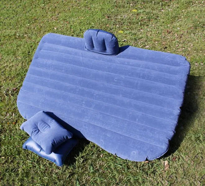 Black inflatable car bed with flocked material and two pillows, set up in a car's rear seats.