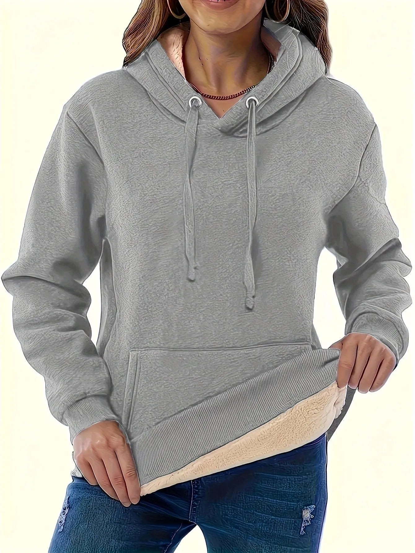 A woman wearing a loose thick black hooded sweater with side pockets and a 3D textured pattern.