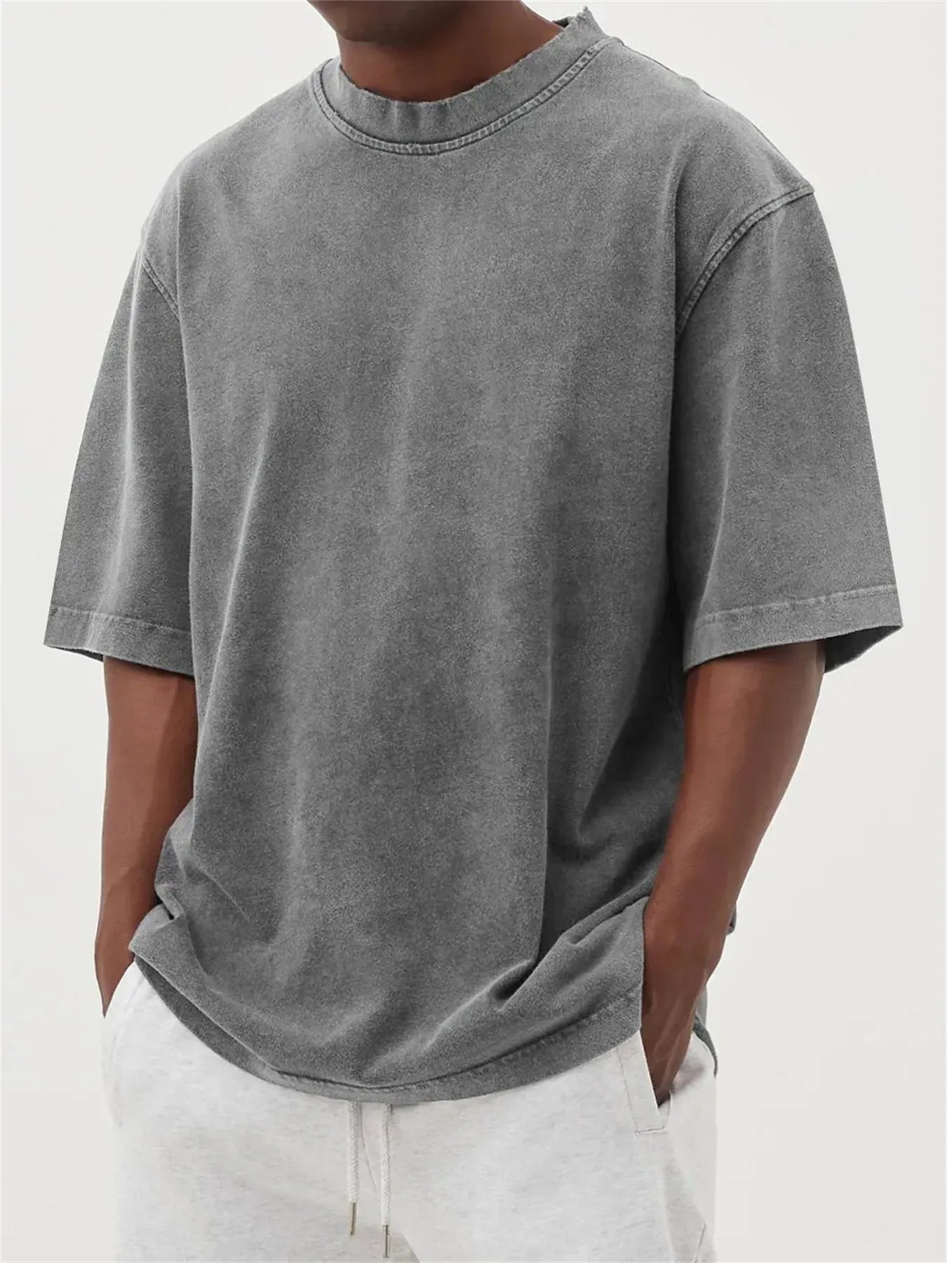 Man wearing a loose-fit, stone-washed distressed pullover T-shirt in a solid colour.