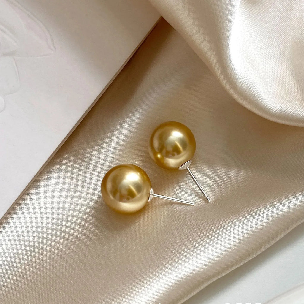 A pair of large silver pearl stud earrings with an eight-pointed star geometric design on a white background.