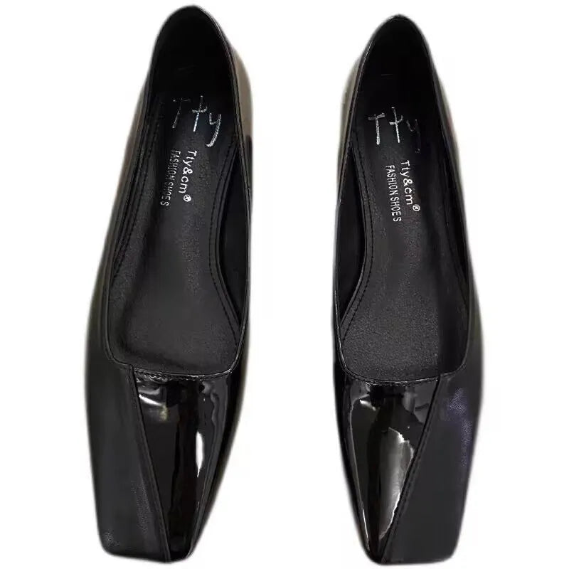 Women's low heel square toe retro pumps in black PU leather with short chunky heel, side view on light background