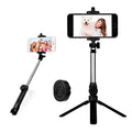 Black Bluetooth selfie tripod with extended stand and 360-degree rotating phone clip attached to an iPhone.