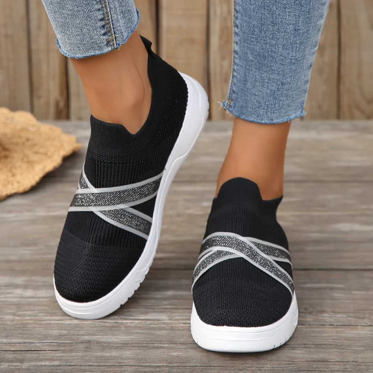 Black women's flyknit mesh casual shoes with a flat rubber sole and a tassel detail on the upper.