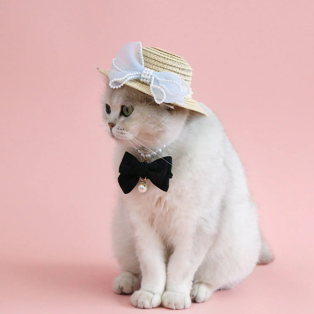 Woven straw hat for a cat with a pearl butterfly bow, shown in pink, purple, blue, or white colour options.