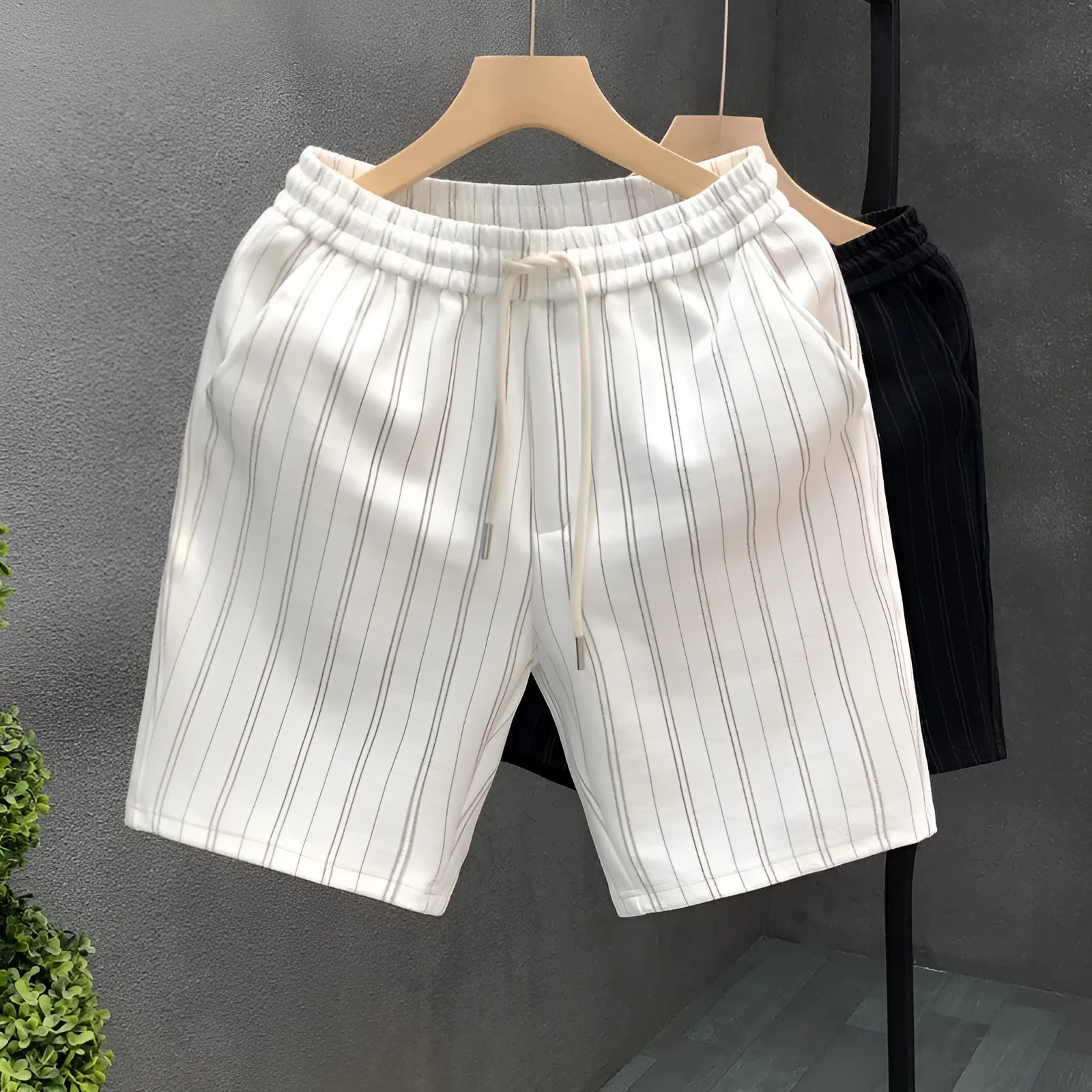 Men's black and white striped casual shorts with elastic waistband, shown on a hanger.