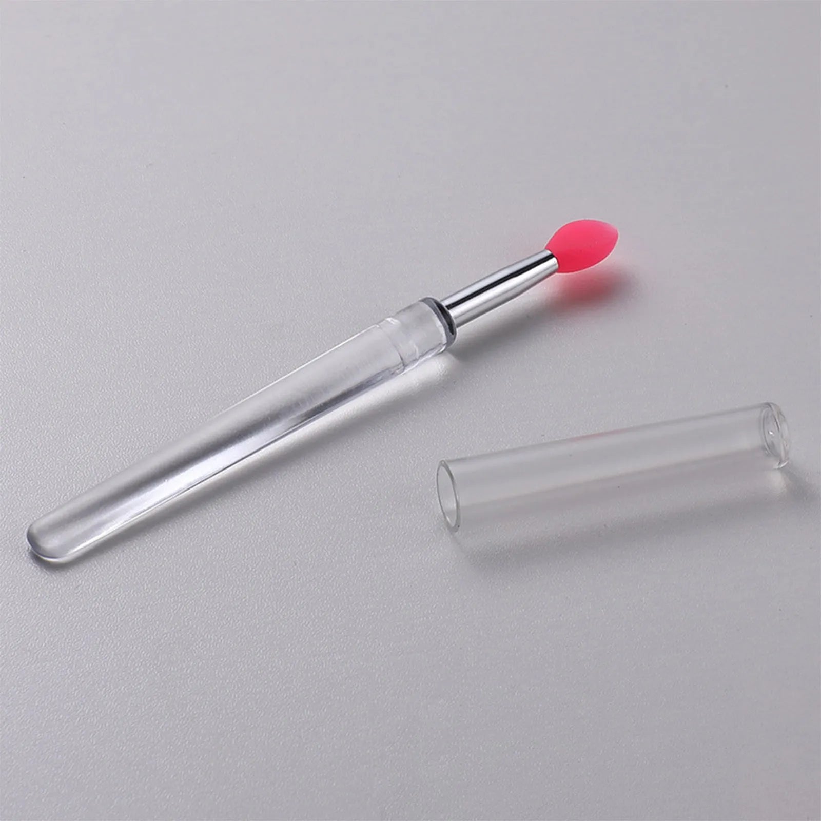 Set of eight colourful reusable silicone lip brushes with hygienic protective caps laid out.