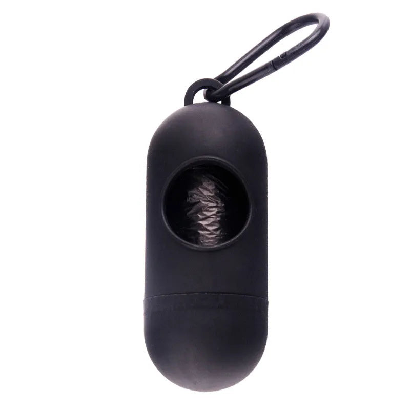 Compact black dog waste bag dispenser with a metal hook and Velcro strap, shown attached to a dog lead.