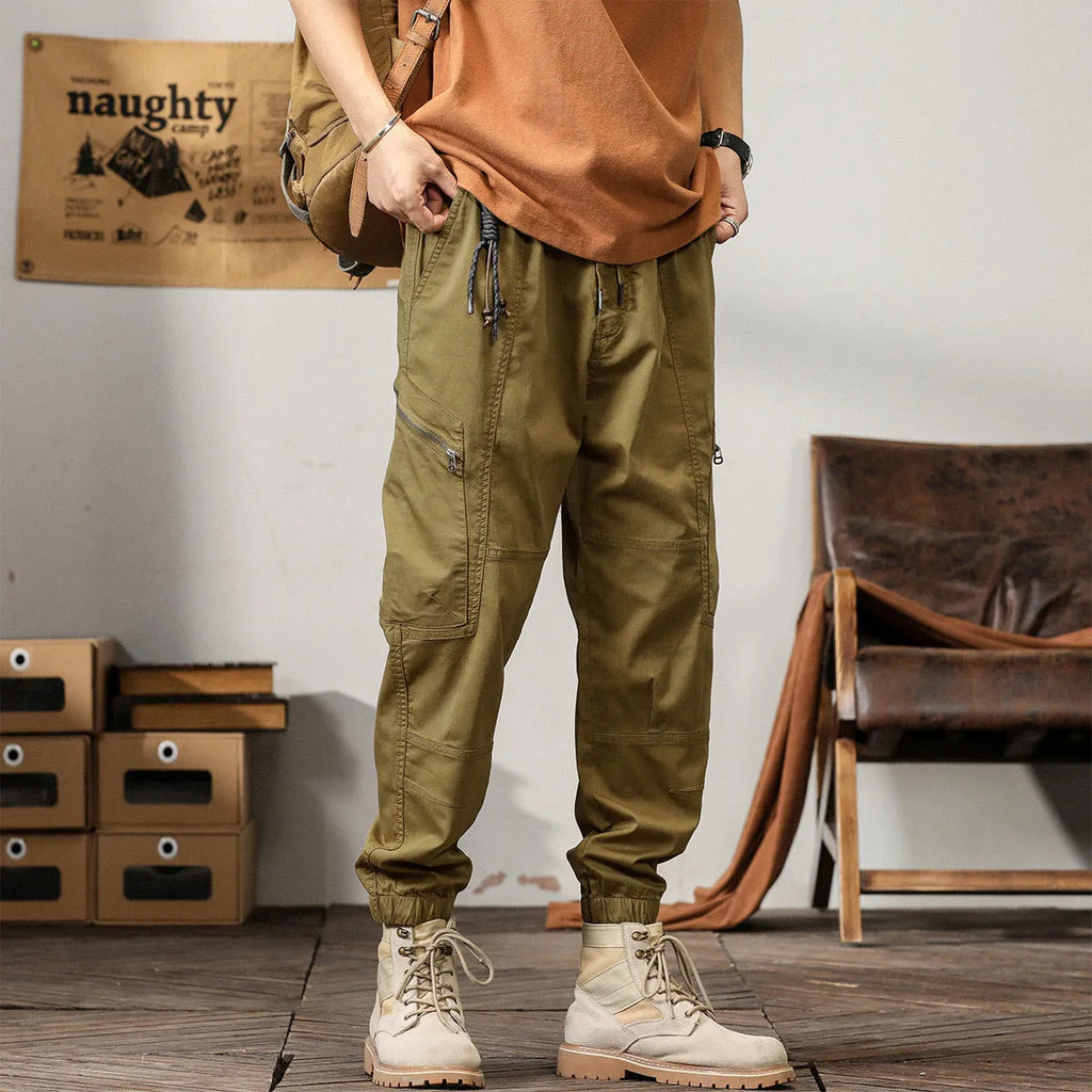 Men's khaki cotton harem pants with tapered ankle bands and a mid-waist zip fly.