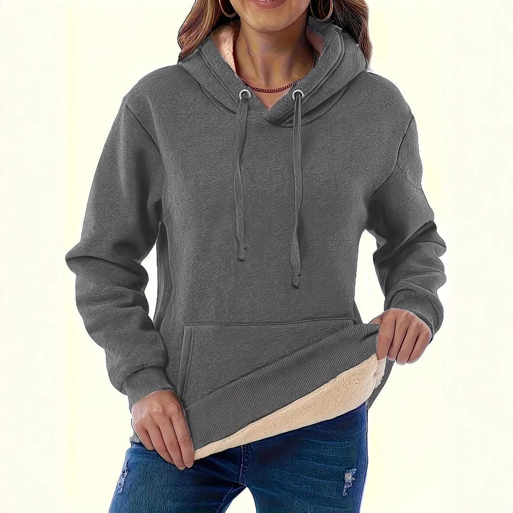 A woman wearing a loose thick black hooded sweater with side pockets and a 3D textured pattern.