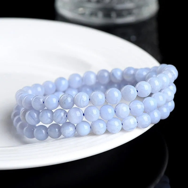 Blue agate bracelet with scattered beads pattern and a Ruyi charm on a white background.