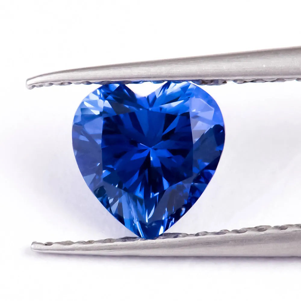 Royal blue loose cultured gemstone in heart, round, and pear shapes on a grey background.