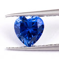 Royal blue loose cultured gemstone in heart, round, and pear shapes on a grey background.