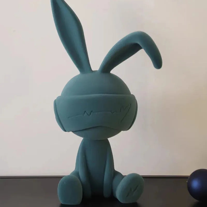 Green resin blindfold rabbit table ornament on a wooden surface.