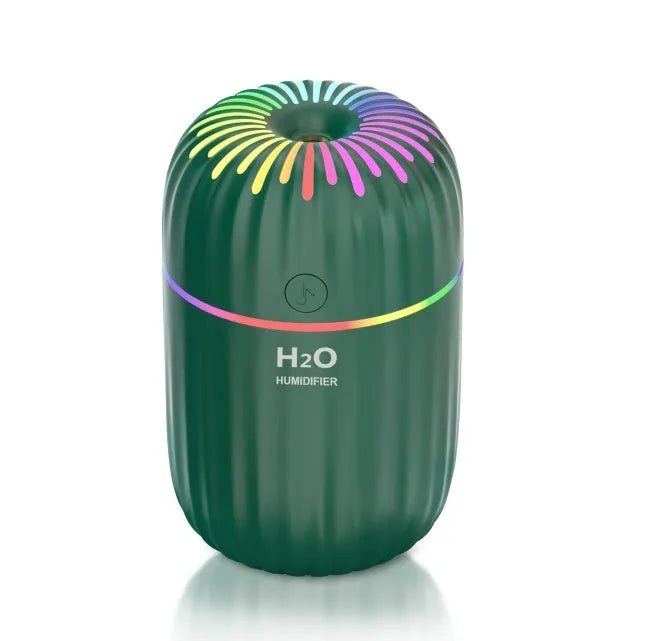 White USB personal mini humidifier with fireworks design on a wooden desk next to a laptop.
