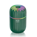 White USB personal mini humidifier with fireworks design on a wooden desk next to a laptop.