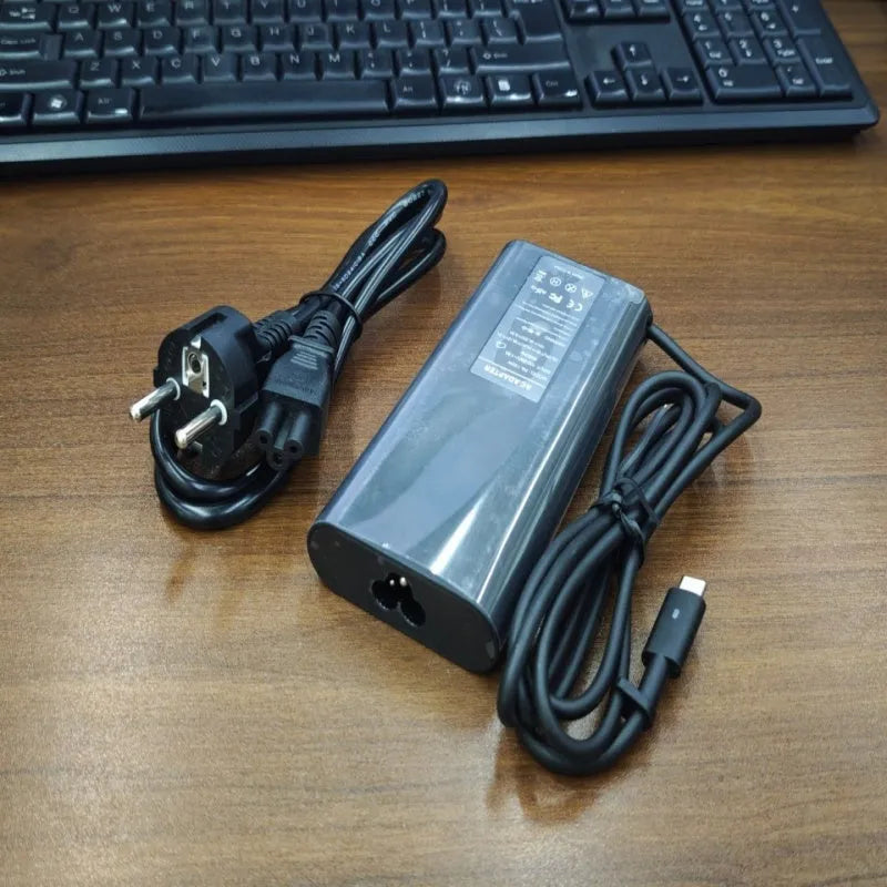Black 65W USB-C laptop power adapter with six international travel plug cords.