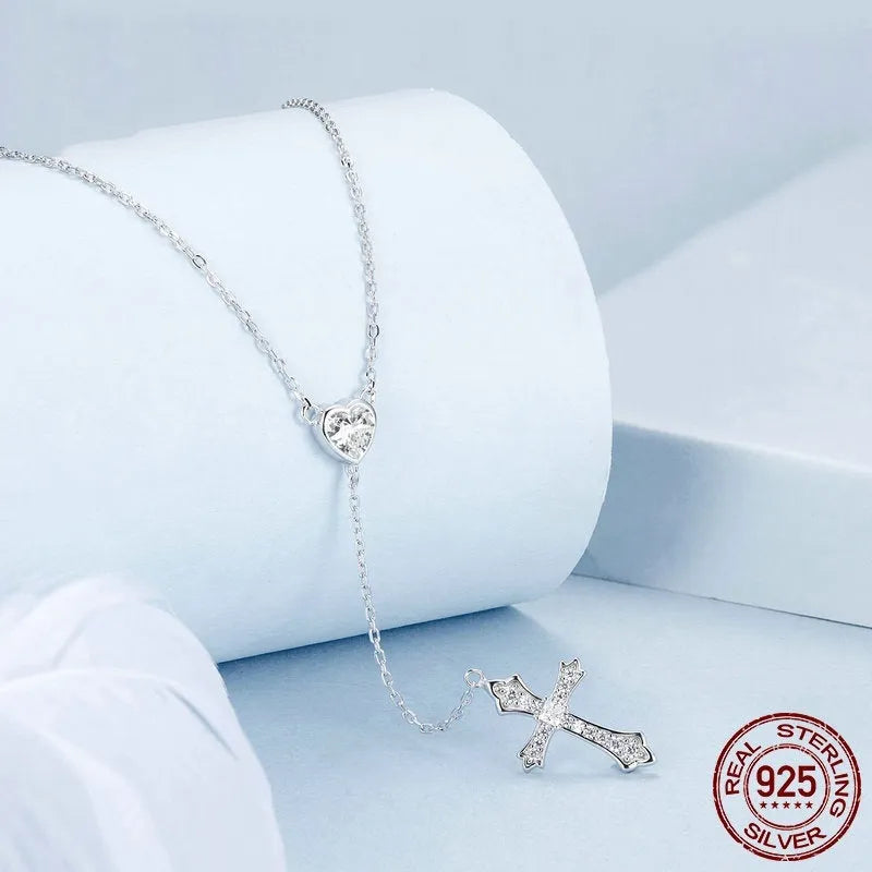 Close-up of a delicate silver love cross pendant on a thin O-ring chain, designed for V-neck wear.