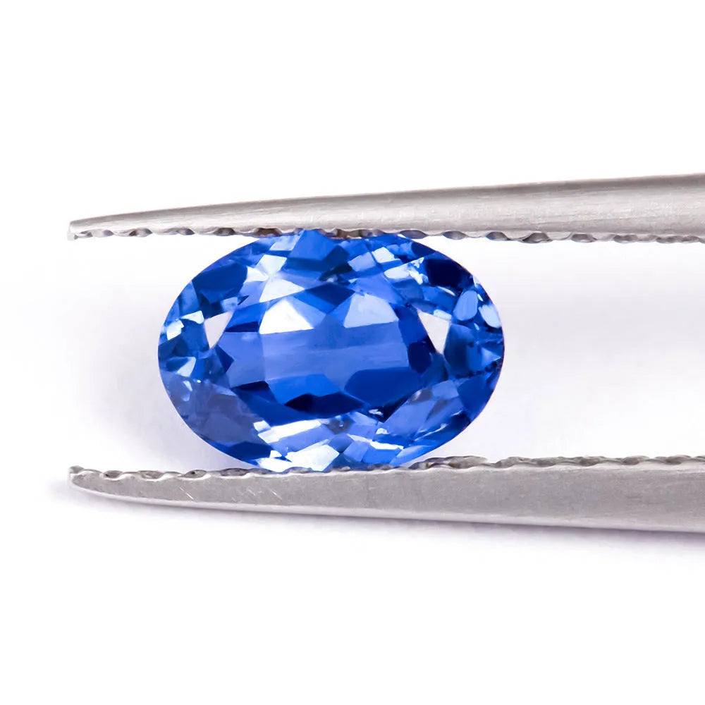 Royal blue loose cultured gemstone in heart, round, and pear shapes on a grey background.