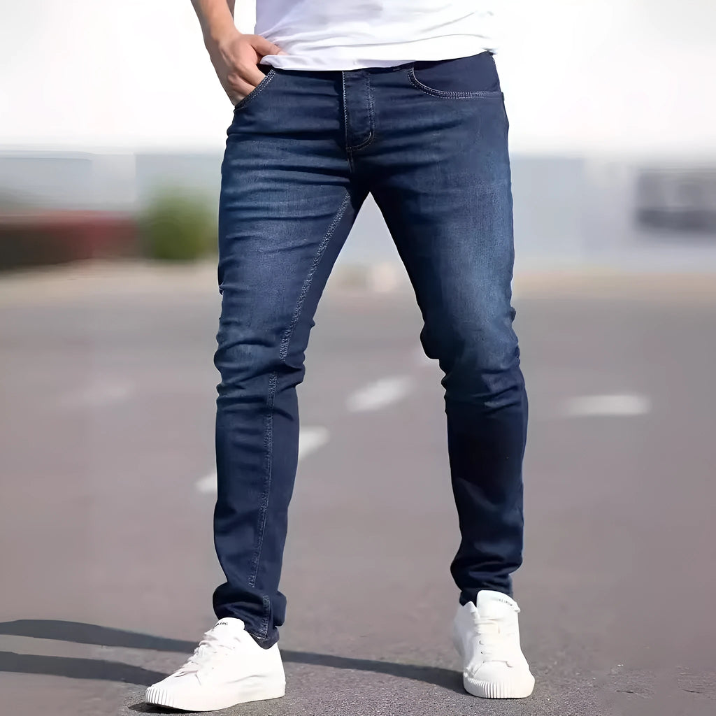 Men's dark blue slim fit skinny jeans with a mid waist and zipper fly, laid flat.