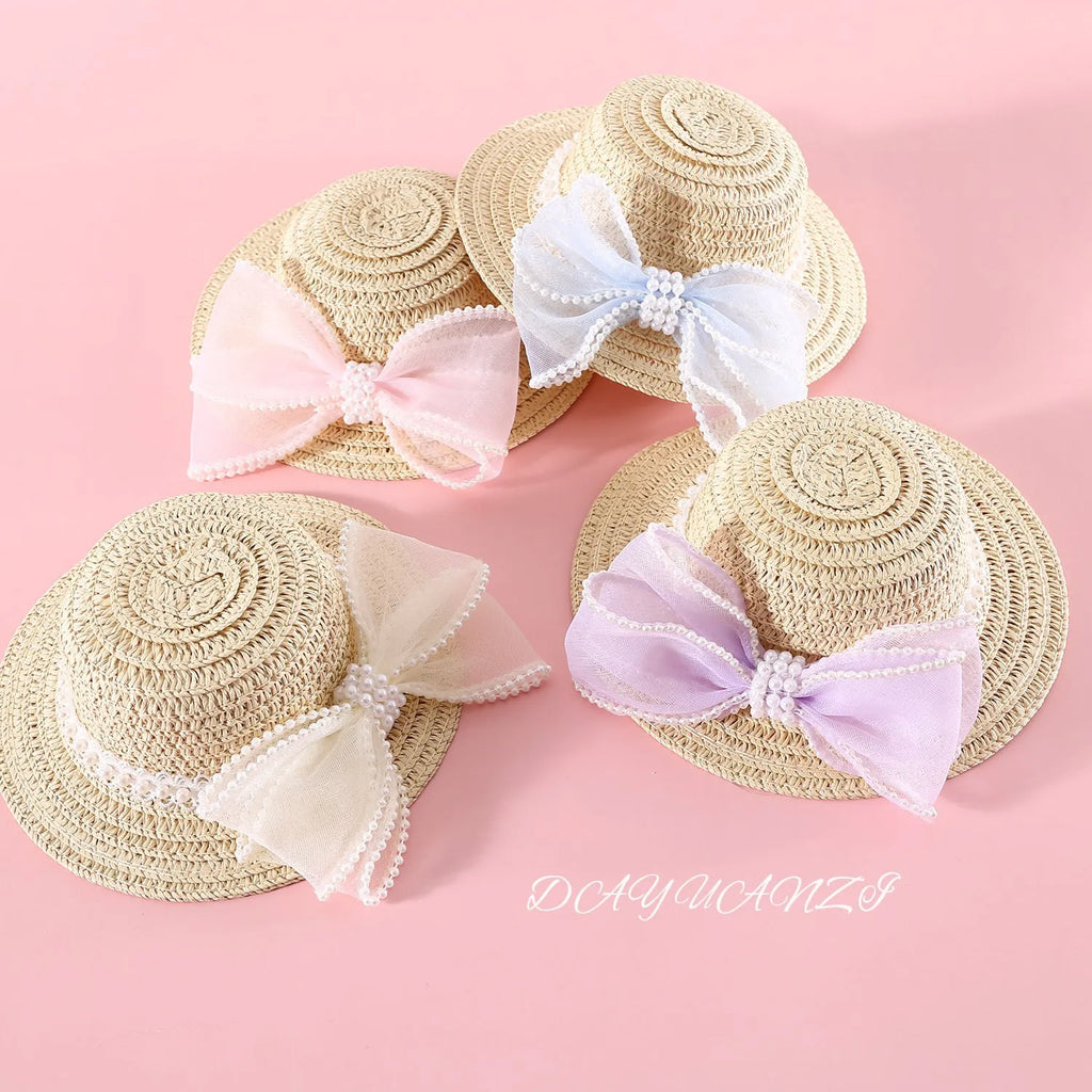 Woven straw hat for a cat with a pearl butterfly bow, shown in pink, purple, blue, or white colour options.