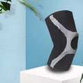 Knitted non-slip sports knee pads in red and grey, showing silicone protective section on knee.