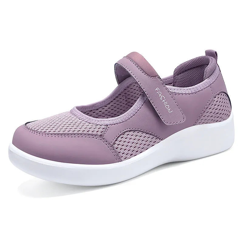 Women's grey casual slip-on shoe with mesh upper and Velcro strap on a flat sole.