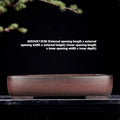Handmade antique-style rectangular purple clay flower pot on a wooden surface.