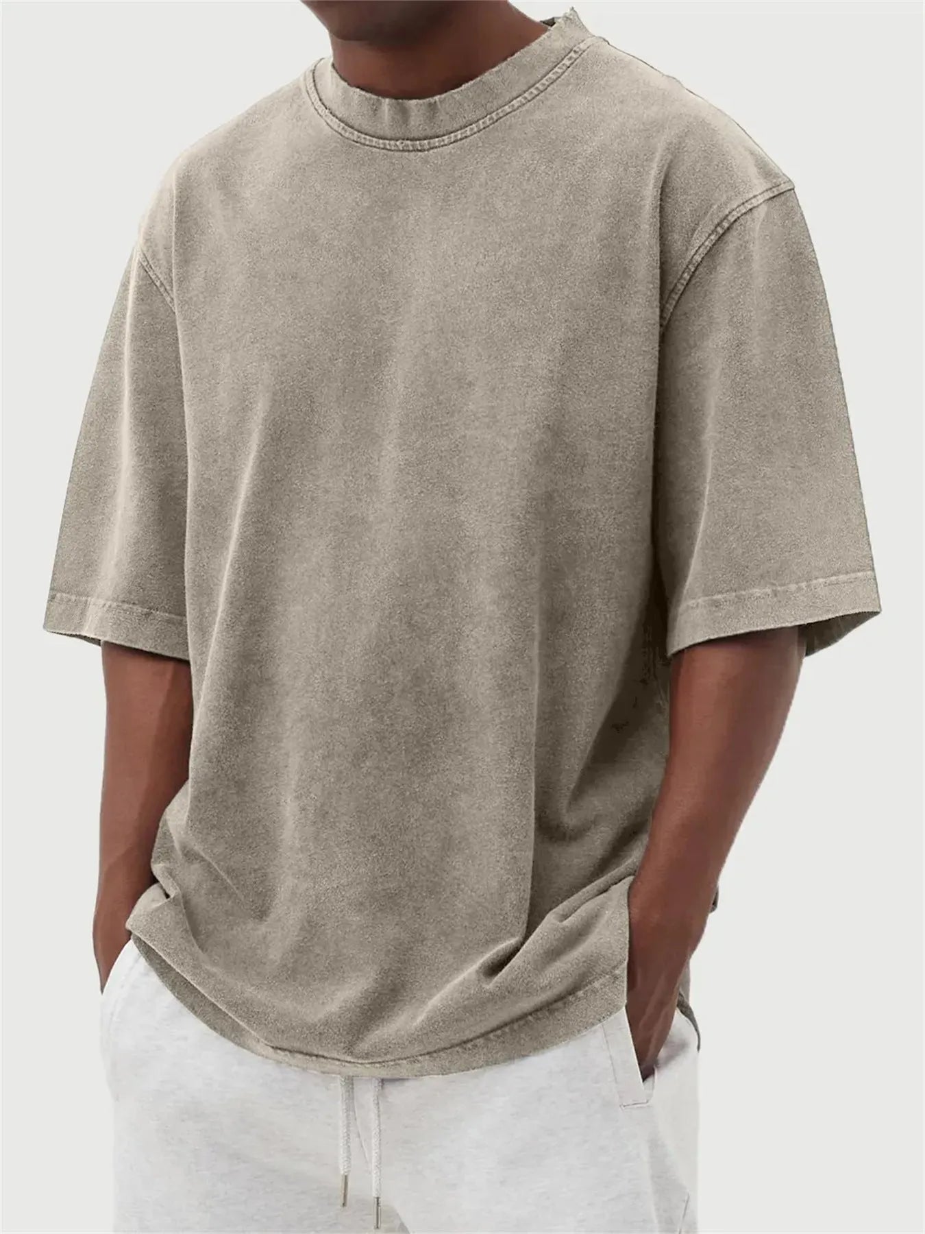 Man wearing a loose-fit, stone-washed distressed pullover T-shirt in a solid colour.