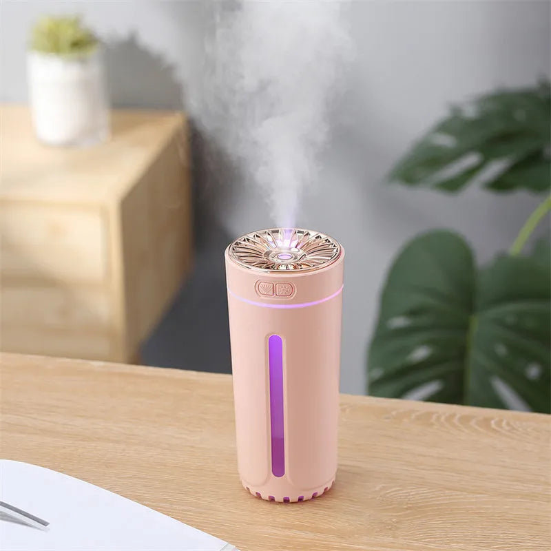 Black portable ultrasonic humidifier with colourful LED lights, shown next to a USB cable on a desktop.