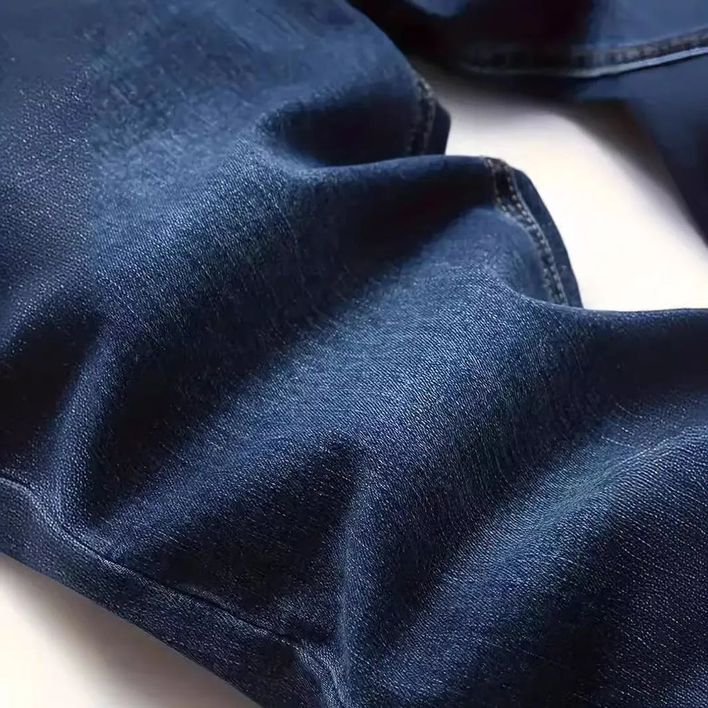 Men's dark blue slim fit skinny jeans with a mid waist and zipper fly, laid flat.