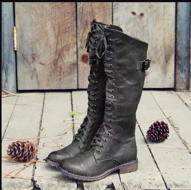Women's black chunky heel high leg boots with a round toe on a plain background.