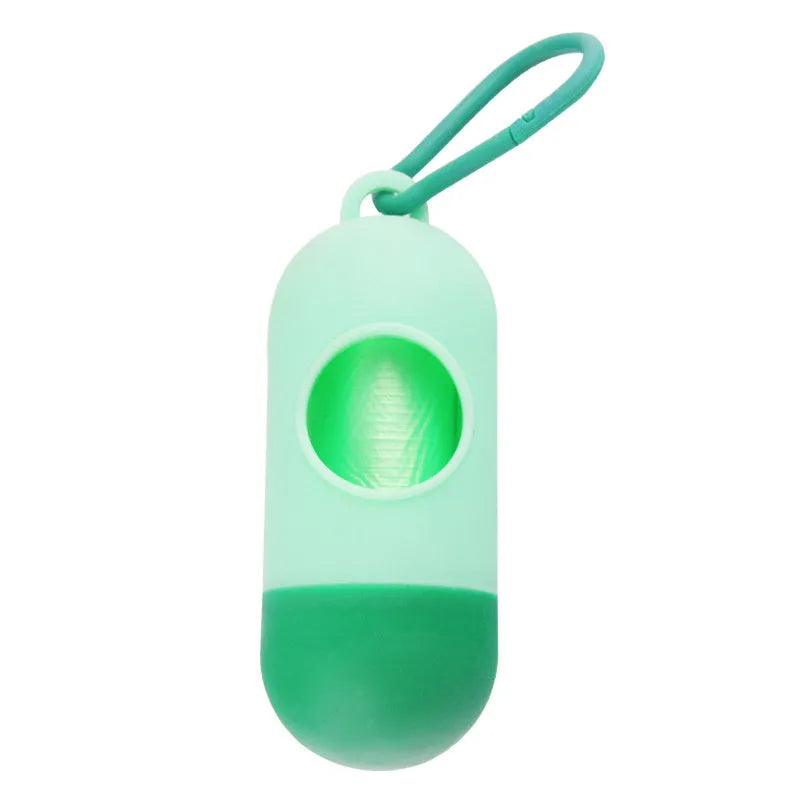 Compact black dog waste bag dispenser with a metal hook and Velcro strap, shown attached to a dog lead.