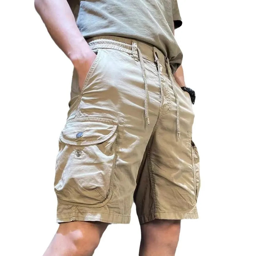 A model wearing loose straight-leg multi-pocket overalls in a khaki colour.
