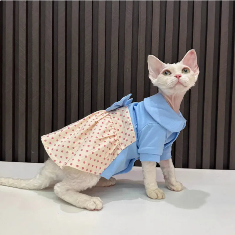 Hairless cat wearing a polka dot skirt with a detachable bow, lying down