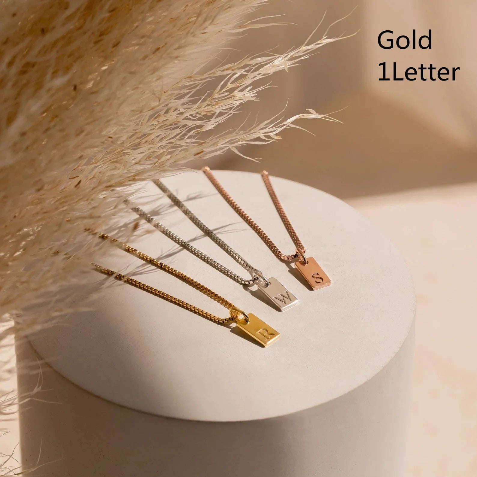 Mini square stainless steel initial necklace with gold plating on a sparkling box chain
