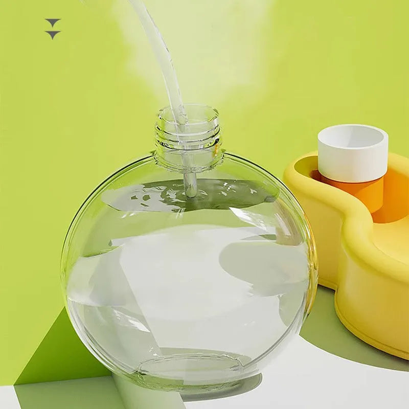 Green and orange portable dog water bottle with pull-out drinking bowl, shown next to a backpack for scale.