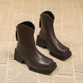 Women's black platform Martin ankle boots with a square toe, chunky sole, and back zipper.