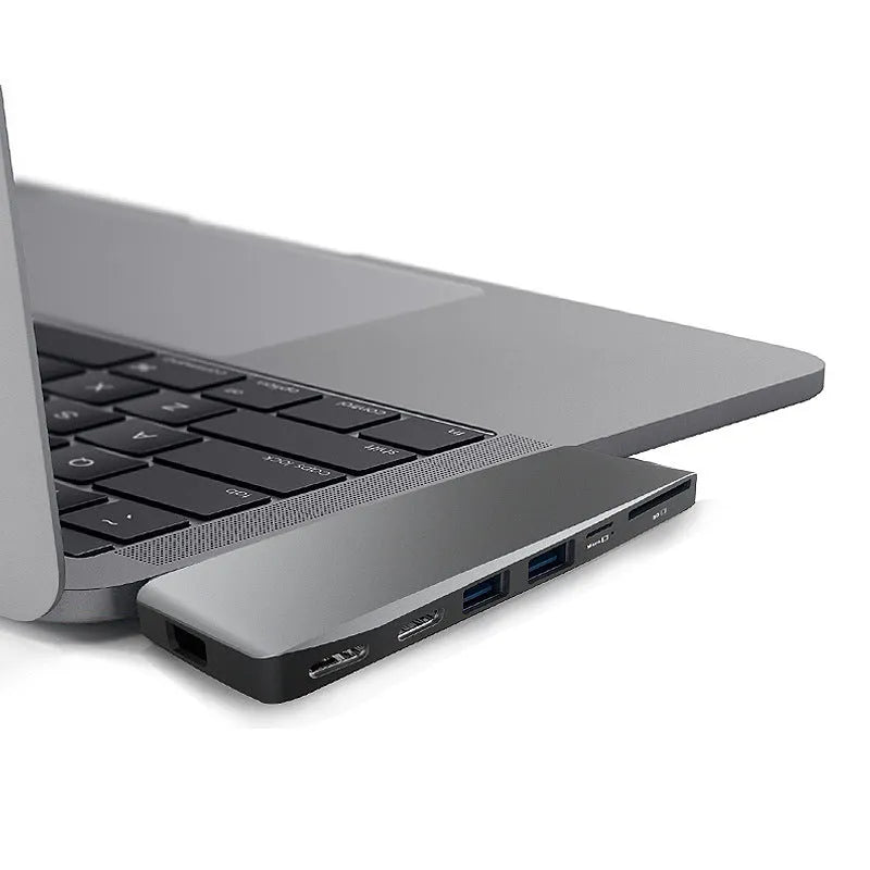 Silver USB-C hub with multiple ports for MacBook Pro, showing USB, card slots, and charging port