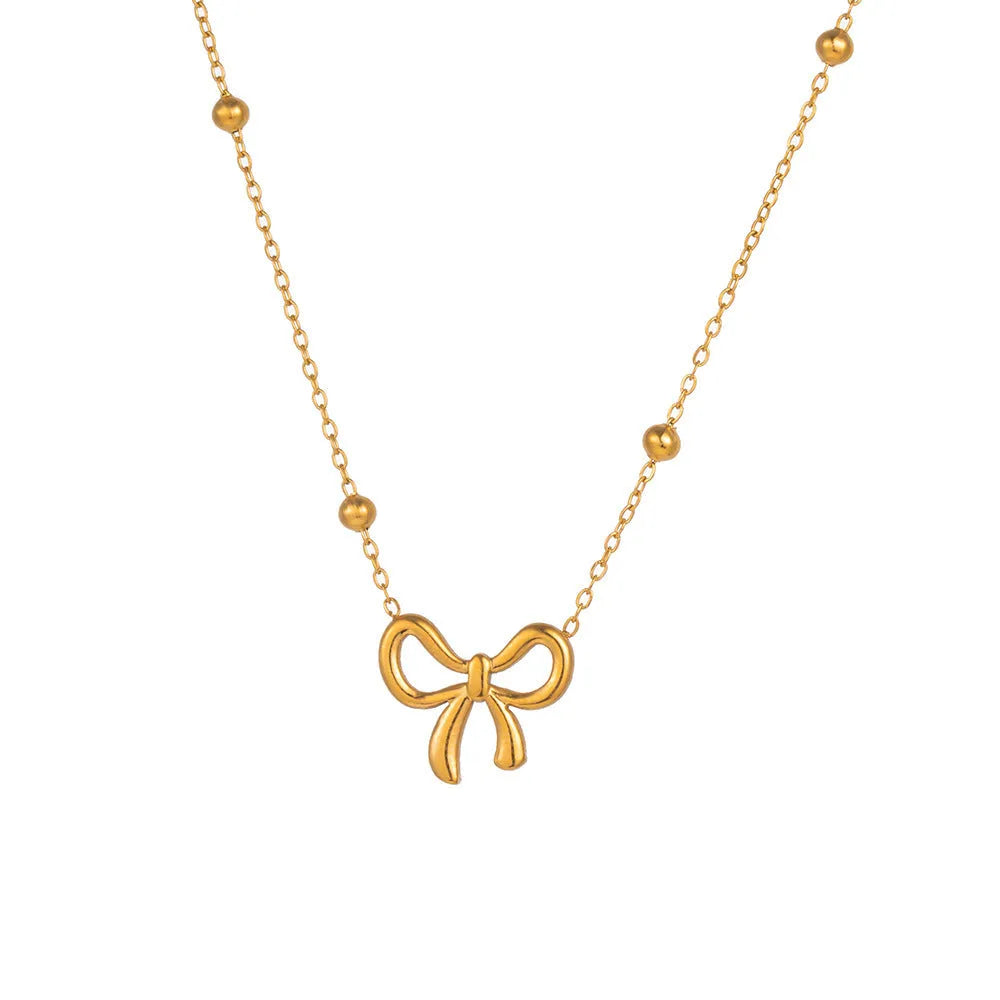 Gold electroplated bow design necklace with cross chain on white background