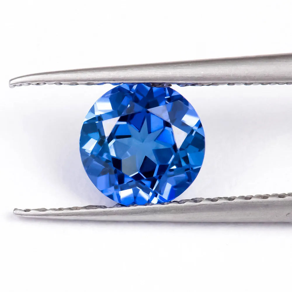 Royal blue loose cultured gemstone in heart, round, and pear shapes on a grey background.