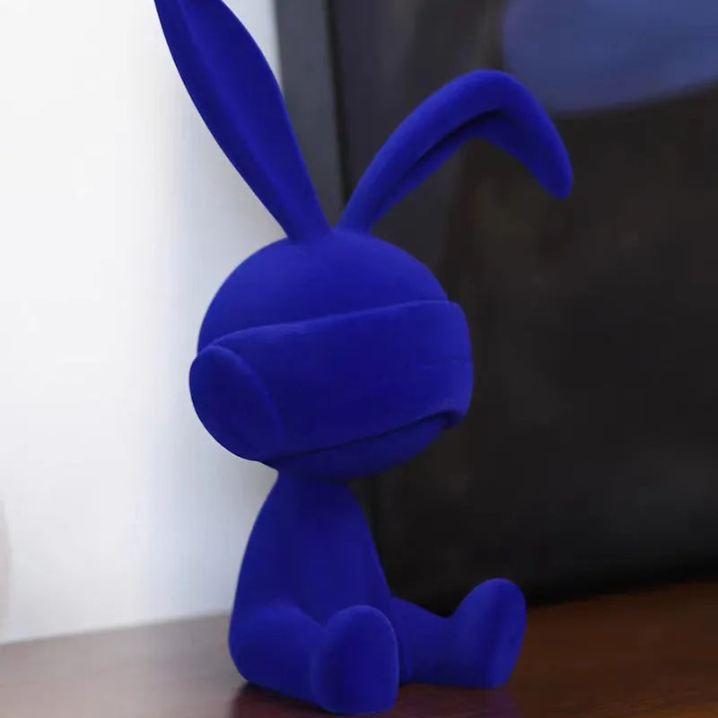Green resin blindfold rabbit table ornament on a wooden surface.