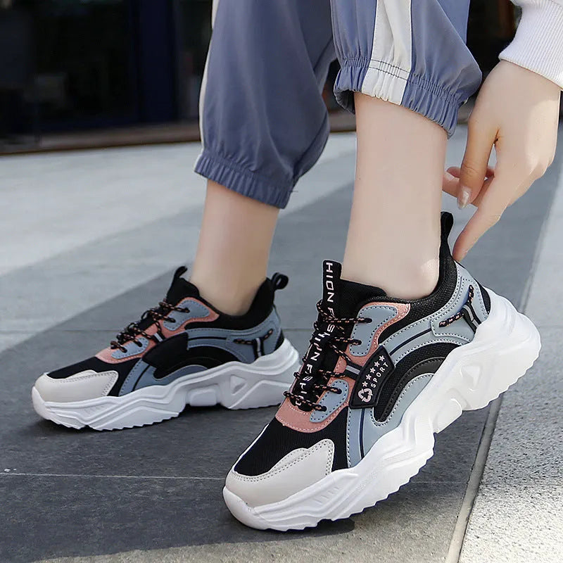 Women's white thick-soled casual sneakers with mesh upper and buckle detail on a light background.
