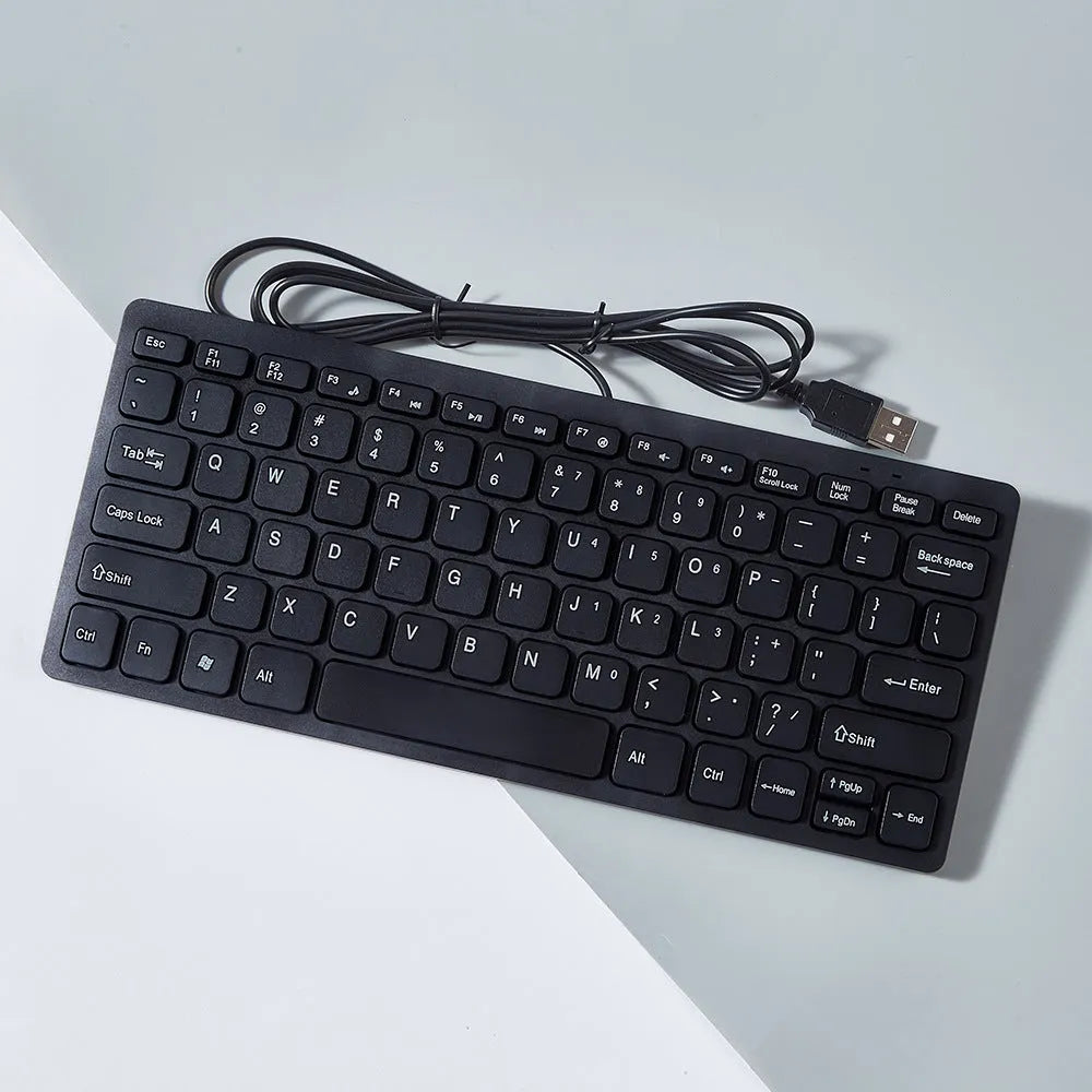 Compact USB wired keyboard in black, white, pink, or blue colour options on a desk.