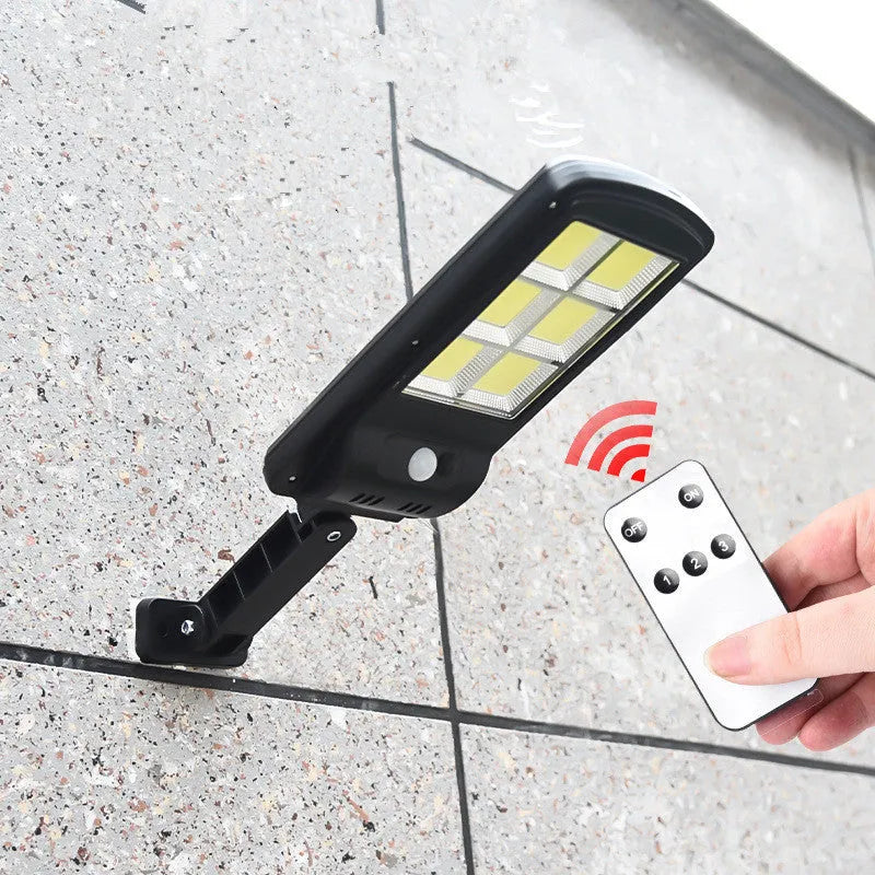 Black solar-powered outdoor motion sensor light mounted on a wall or post.