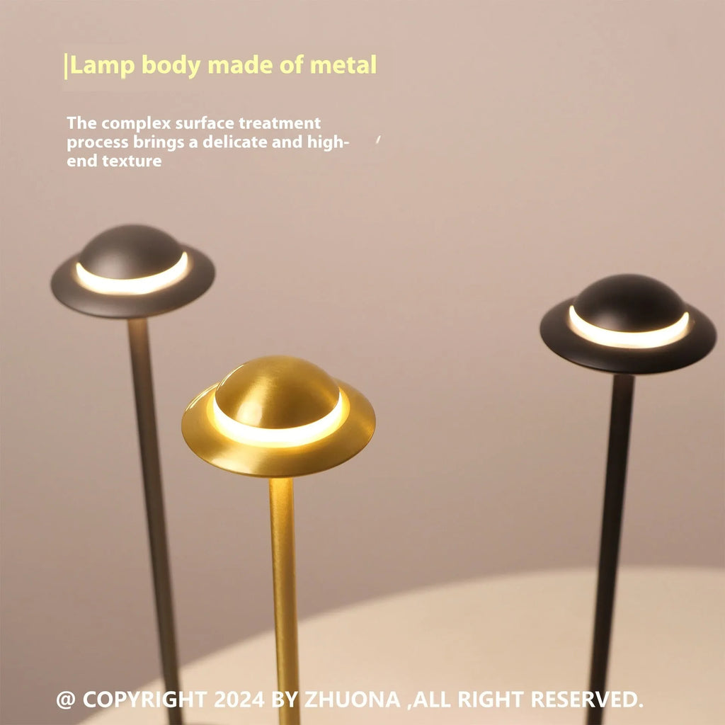 Metallic UFO-shaped desk lamp with touch controls in black finish on wooden surface